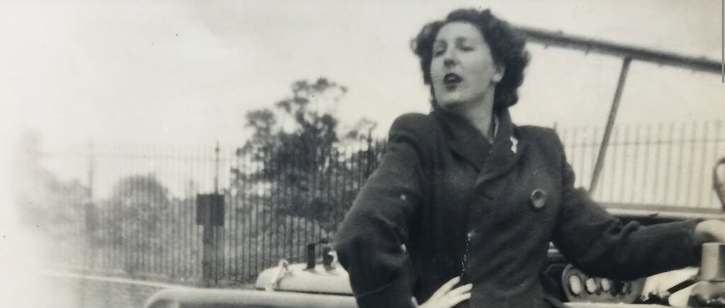 A vintage black and white photo of a lady called Dorothy Peters, standing to the side of a Land Rover Series 1