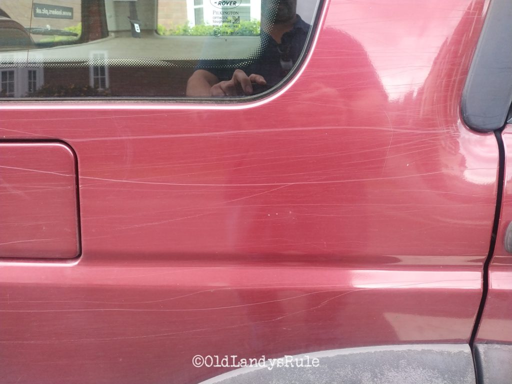 Close up of the rear quarter of a red Discovery 2 with scratch marks