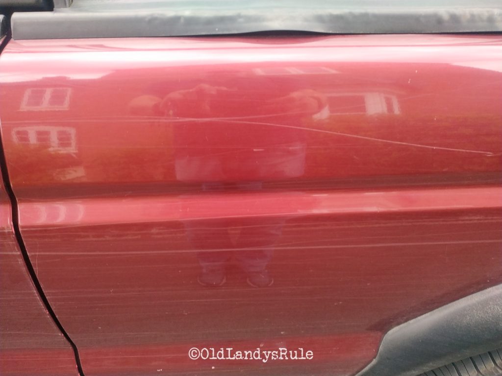 Close up of the rear door of a red Discovery 2 with scratch marks