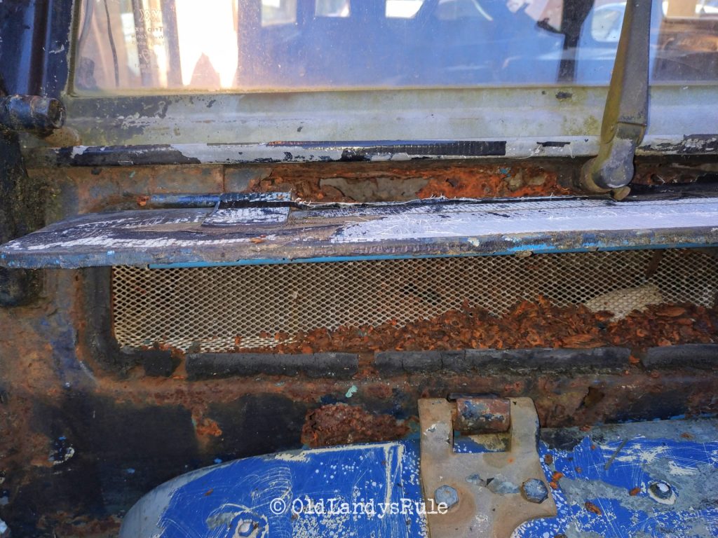 Close up of a Land Rover Series 3's bulkhead vent, and the mountains of rust plaguing it.