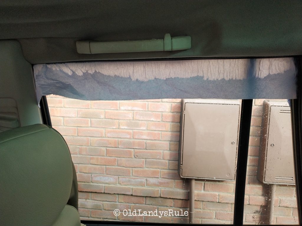 Looking out the rear right side window of a Land Rover Discovery 2, with blue paper towel tucked in the top, which is soaking with water