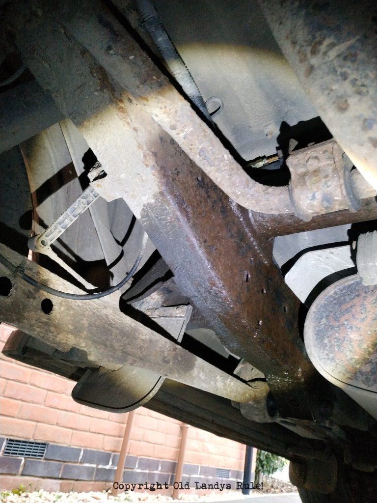 Underneath the rear of a Land Rover Discovery 2, looking up at the chassis which is wet with brake fluid